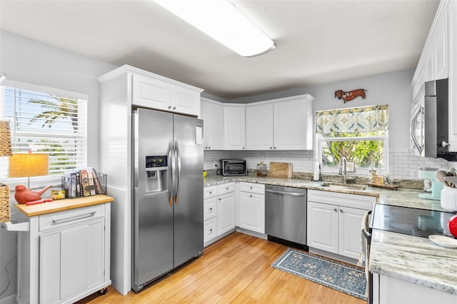 7950 Causeway Blvd N, Saint Petersburg, FL 33707 - kitchen featuring stainless steel appliances, backsplash, and white cabinetry