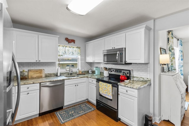 7950 Causeway Blvd N, Saint Petersburg, FL 33707 - kitchen with stainless steel appliances, white cabinets, and light wood-style floors
