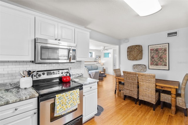 7950 Causeway Blvd N, Saint Petersburg, FL 33707 - kitchen featuring appliances with stainless steel finishes, tasteful backsplash, light wood-type flooring, and white cabinets
