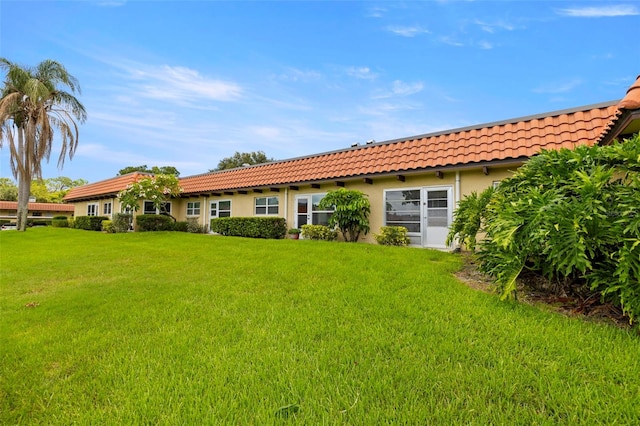 1701 Pinehurst Rd Unit 18D, Dunedin, FL 34698 - back of house featuring a tile roof, stucco siding, and a yard