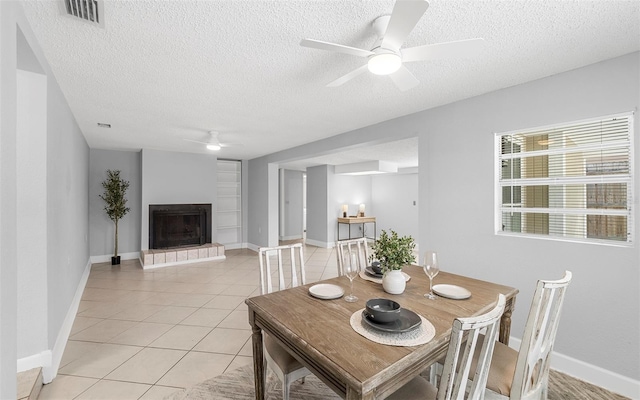2614 W Idlewild Ave, Tampa, FL 33614 - dining room featuring a ceiling fan, a textured ceiling, light tile patterned flooring, and a fireplace with raised hearth