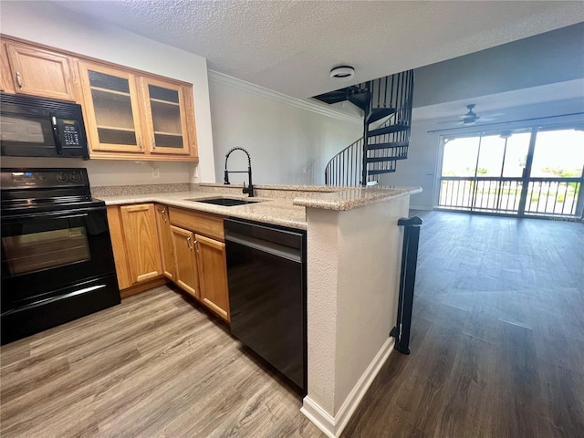 2400 Feather Sound Dr Unit 935, Clearwater, FL 33762 - kitchen featuring black appliances, a peninsula, light wood-style flooring, ornamental molding, and open floor plan