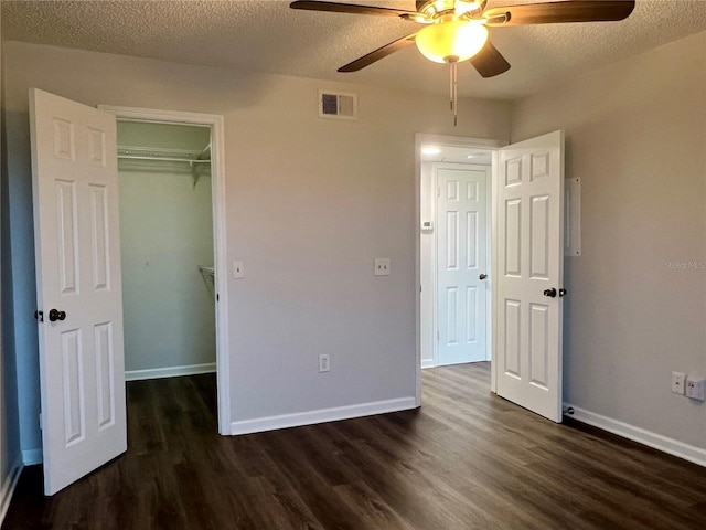 2400 Feather Sound Dr Unit 935, Clearwater, FL 33762 - unfurnished bedroom featuring dark wood-style flooring, a textured ceiling, ceiling fan, and a walk in closet