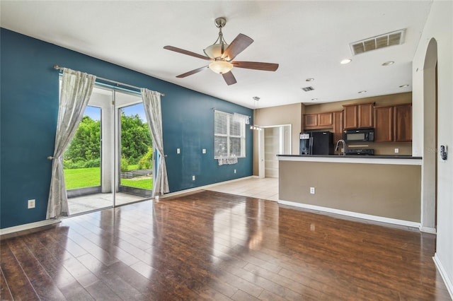 10343 Avelar Ridge Dr, Riverview, FL 33578 - kitchen with black appliances, ceiling fan, dark countertops, light wood-type flooring, and brown cabinets