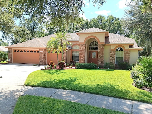 3740 Emerald Ln, Mulberry, FL 33860 - mediterranean / spanish-style house with an attached garage, concrete driveway, a front yard, stucco siding, and roof with shingles
