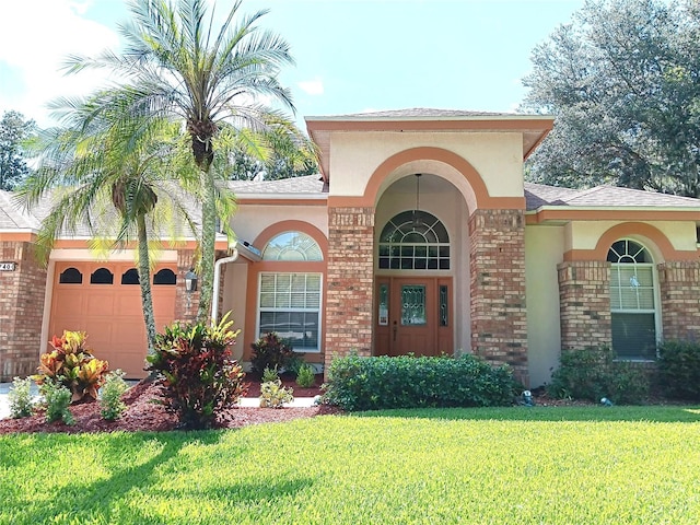 3740 Emerald Ln, Mulberry, FL 33860 - view of front of house featuring an attached garage, brick siding, a front lawn, stucco siding, and a shingled roof