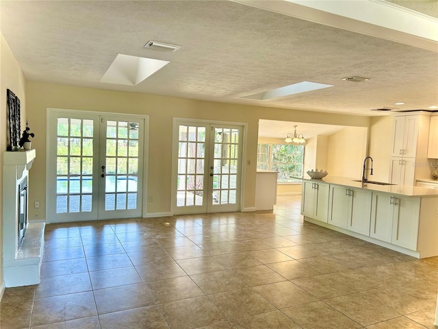 17017 Paula Ln, Lutz, FL 33558 - kitchen with french doors, a skylight, a textured ceiling, a chandelier, and light countertops