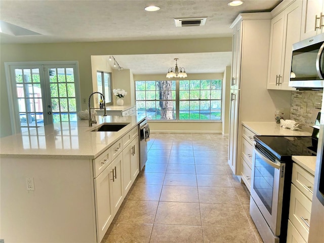 17017 Paula Ln, Lutz, FL 33558 - kitchen with appliances with stainless steel finishes, a chandelier, white cabinets, an island with sink, and light tile patterned floors