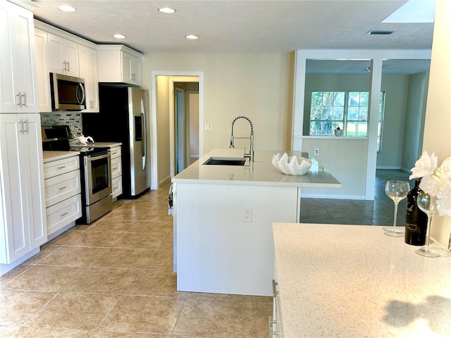 17017 Paula Ln, Lutz, FL 33558 - kitchen with appliances with stainless steel finishes, white cabinets, decorative backsplash, a kitchen island with sink, and recessed lighting