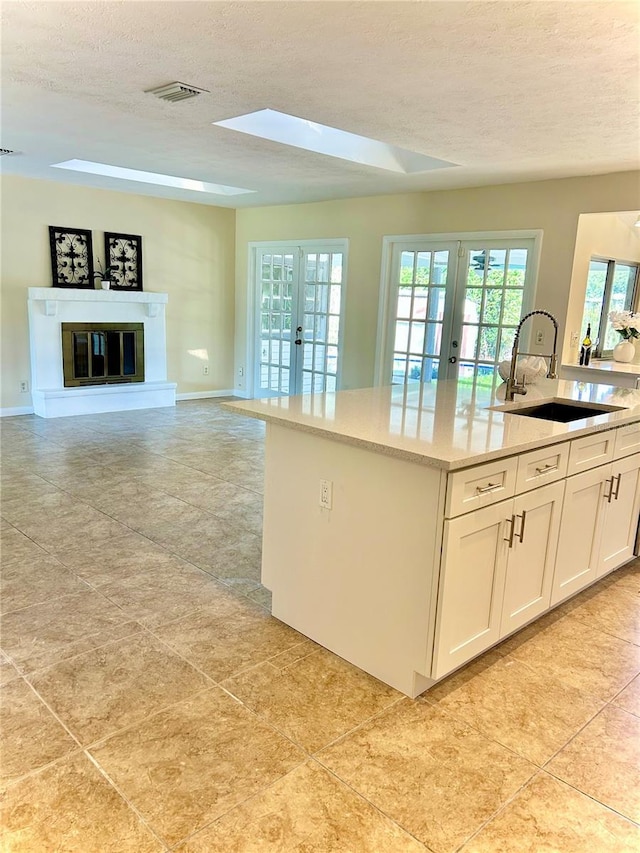 17017 Paula Ln, Lutz, FL 33558 - kitchen with french doors, a textured ceiling, white cabinets, a glass covered fireplace, and open floor plan