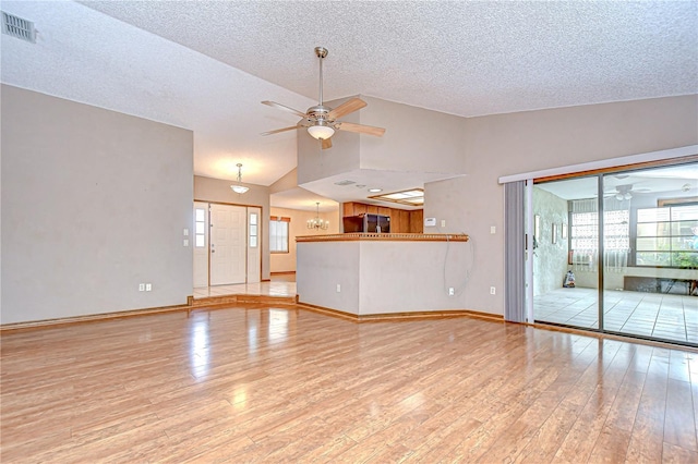 11070 Tilburg St, Spring Hill, FL 34608 - unfurnished living room featuring a ceiling fan, lofted ceiling, light wood-style floors, a textured ceiling, and a chandelier