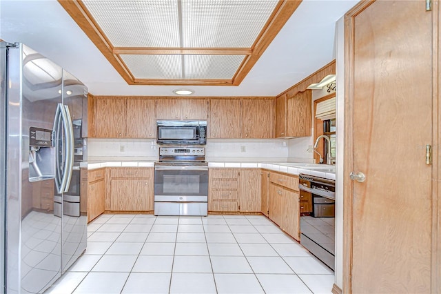 11070 Tilburg St, Spring Hill, FL 34608 - kitchen featuring stainless steel appliances, tile countertops, a raised ceiling, tasteful backsplash, and light brown cabinets