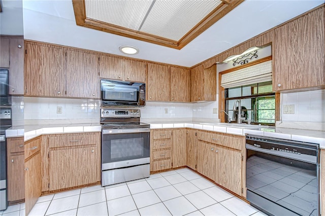 11070 Tilburg St, Spring Hill, FL 34608 - kitchen with black appliances, a tray ceiling, backsplash, and tile counters