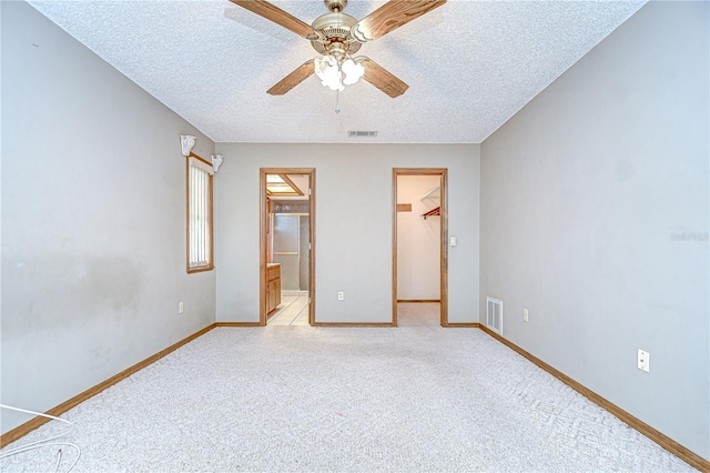 11070 Tilburg St, Spring Hill, FL 34608 - unfurnished bedroom featuring light carpet, a walk in closet, a textured ceiling, a ceiling fan, and ensuite bath