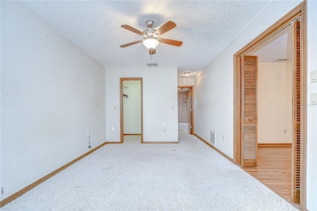 11070 Tilburg St, Spring Hill, FL 34608 - unfurnished bedroom with a spacious closet, a textured ceiling, a closet, light carpet, and ceiling fan