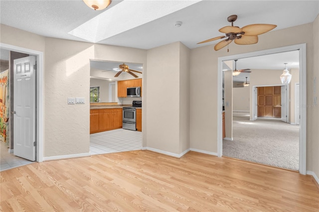 8470 Cranes Roost Dr, New Port Richey, FL 34654 - kitchen featuring stainless steel appliances, a skylight, a ceiling fan, and light wood-style floors