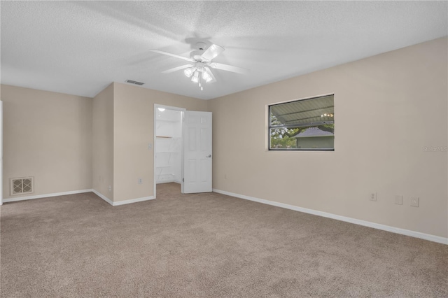 8470 Cranes Roost Dr, New Port Richey, FL 34654 - unfurnished bedroom with carpet floors, a walk in closet, a textured ceiling, a ceiling fan, and a closet