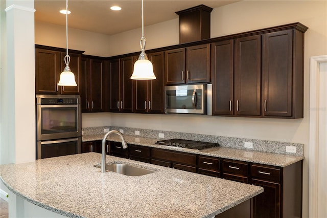 7508 Sea Lilly Ct, Apollo Beach, FL 33572 - kitchen with stainless steel appliances, dark brown cabinetry, a kitchen island with sink, recessed lighting, and light stone counters