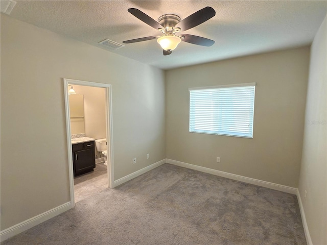 7508 Sea Lilly Ct, Apollo Beach, FL 33572 - unfurnished bedroom with a textured ceiling, light carpet, connected bathroom, and a ceiling fan