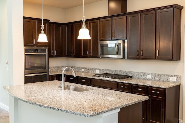 7508 Sea Lilly Ct, Apollo Beach, FL 33572 - kitchen featuring appliances with stainless steel finishes, dark brown cabinets, pendant lighting, and light stone counters