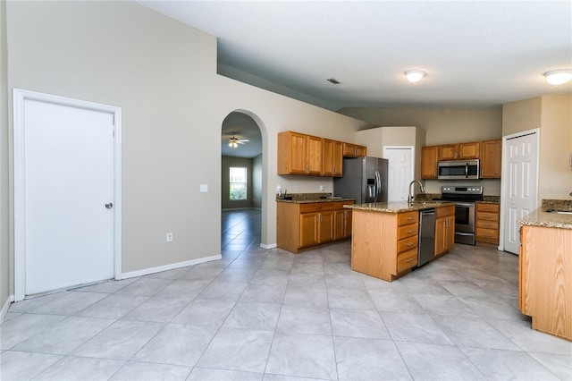 13190 Drysdale St, Spring Hill, FL 34609 - kitchen featuring stainless steel appliances, a center island with sink, light stone countertops, and brown cabinets