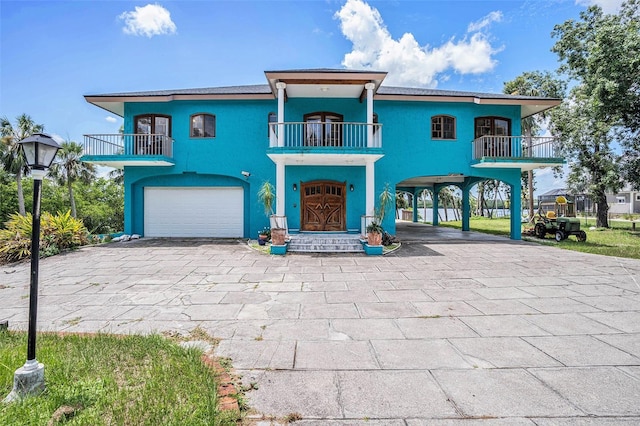 7715 Riverview Dr, Riverview, FL 33578 - coastal inspired home featuring a balcony, a carport, decorative driveway, and a garage
