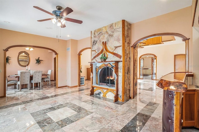 7715 Riverview Dr, Riverview, FL 33578 - living area featuring arched walkways, marble tiled flooring, a ceiling fan, recessed lighting, and a fireplace
