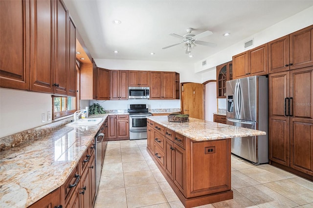 7715 Riverview Dr, Riverview, FL 33578 - kitchen with appliances with stainless steel finishes, a center island, light stone counters, a ceiling fan, and glass insert cabinets