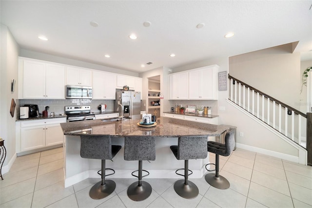 2101 Sunset Wind Loop, Oldsmar, FL 34677 - kitchen with stainless steel appliances, tasteful backsplash, a center island with sink, a kitchen bar, and recessed lighting