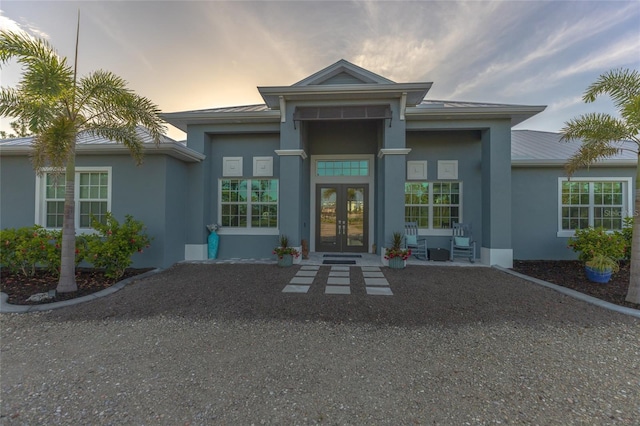 9016 Falcon Ct, Venice, FL 34293 - exterior entry at dusk featuring french doors, stucco siding, a metal roof, and a standing seam roof