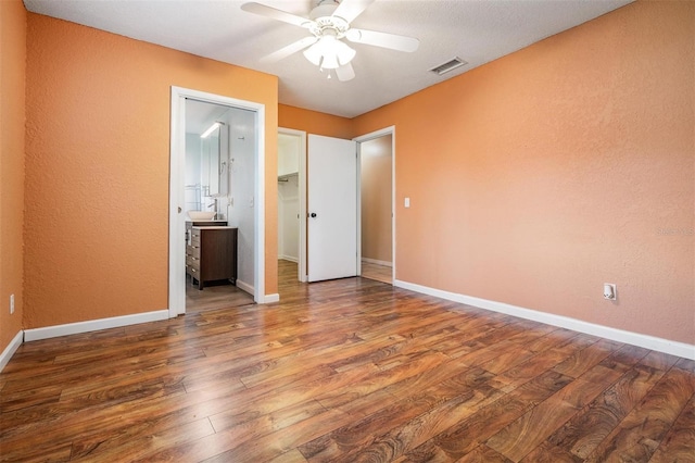 1328 Glenview Ln, Lakeland, FL 33813 - unfurnished bedroom with wood finished floors, ensuite bath, ceiling fan, and a textured wall