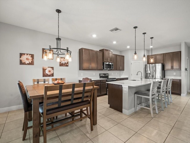 13638 Moosehead Cir, Hudson, FL 34669 - kitchen with stainless steel appliances, a chandelier, light tile patterned floors, light countertops, and an island with sink