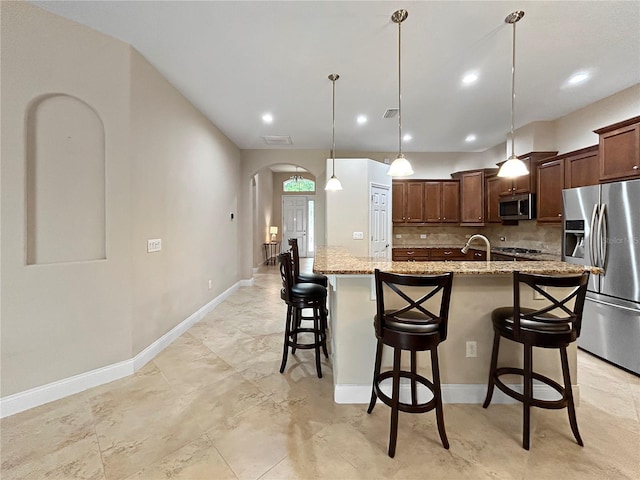 2802 Devonoak Blvd, Land O Lakes, FL 34638 - kitchen with appliances with stainless steel finishes, arched walkways, a large island, a kitchen breakfast bar, and tasteful backsplash