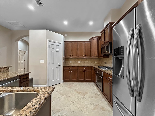 2802 Devonoak Blvd, Land O Lakes, FL 34638 - kitchen featuring stainless steel appliances, arched walkways, backsplash, stone counters, and recessed lighting