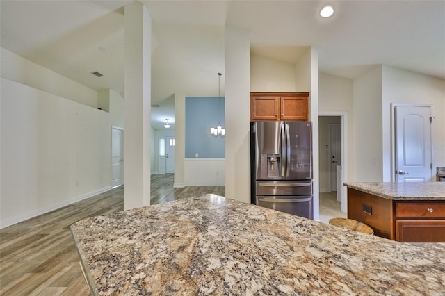 12218 Avondale Oak Pl, Riverview, FL 33578 - kitchen with stainless steel fridge with ice dispenser, light wood-type flooring, brown cabinetry, light stone counters, and a chandelier