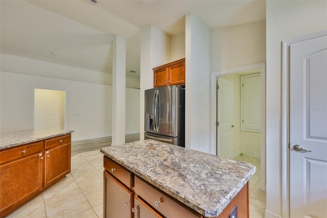 12218 Avondale Oak Pl, Riverview, FL 33578 - kitchen with stainless steel fridge, light stone countertops, light tile patterned floors, and a kitchen island
