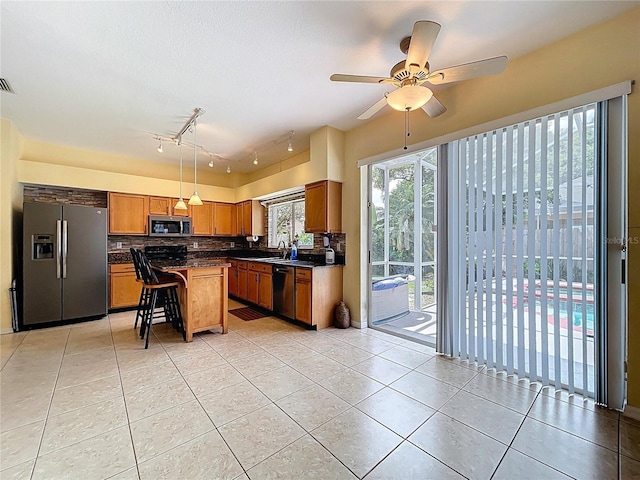 4222 Trumpworth Ct, Valrico, FL 33596 - kitchen with appliances with stainless steel finishes, dark countertops, light tile patterned floors, and a breakfast bar area