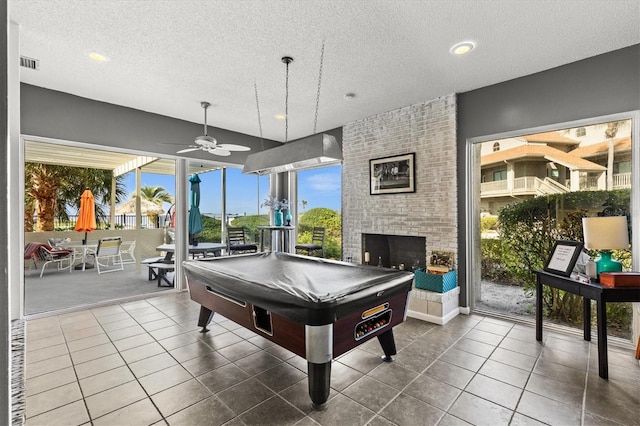 630 Windrush Bay Dr Unit 630, Tarpon Springs, FL 34689 - playroom featuring billiards table, a textured ceiling, a brick fireplace, ceiling fan, and tile patterned floors