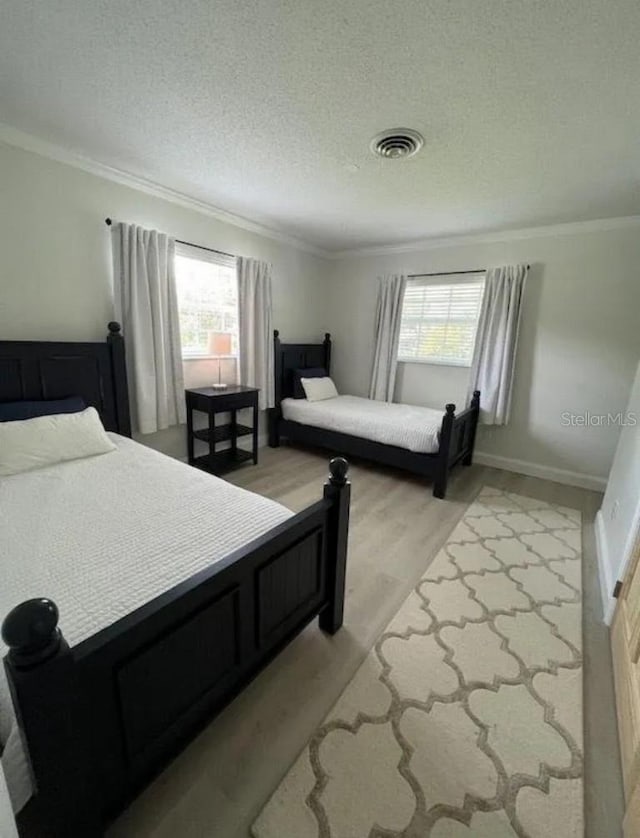 3856 Tarpon Rd, Venice, FL 34293 - bedroom with ornamental molding, multiple windows, light wood-type flooring, and a textured ceiling