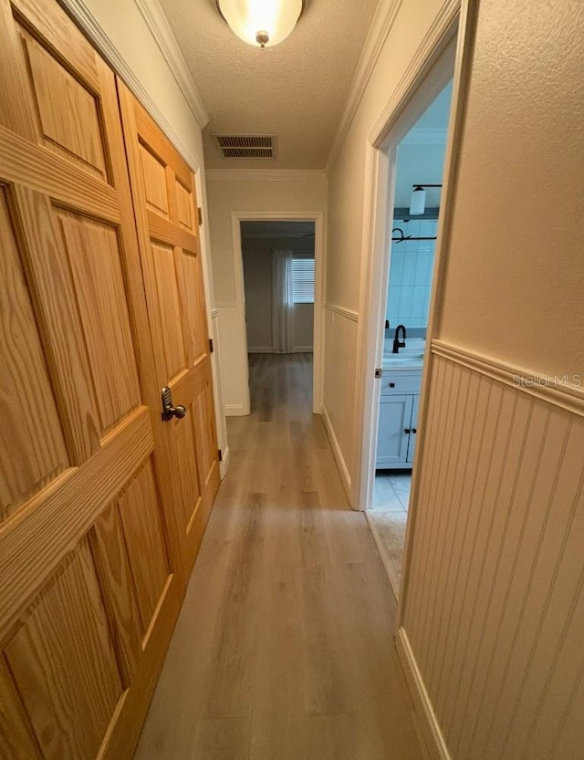 3856 Tarpon Rd, Venice, FL 34293 - hall with light wood-style floors, wainscoting, crown molding, and a textured ceiling