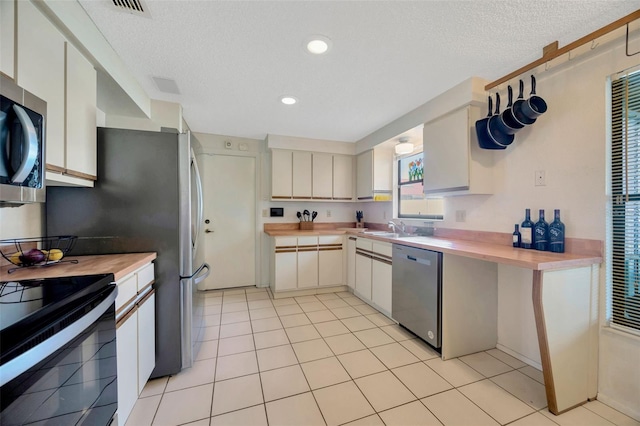 3302 69th St W, Bradenton, FL 34209 - kitchen with stainless steel appliances, butcher block countertops, a textured ceiling, light tile patterned floors, and recessed lighting