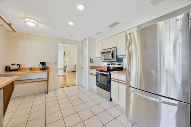 3302 69th St W, Bradenton, FL 34209 - kitchen featuring appliances with stainless steel finishes, a textured ceiling, white cabinets, recessed lighting, and light tile patterned floors