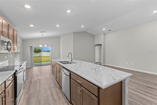 11958 Stone Pine St, Riverview, FL 33569 - kitchen featuring stainless steel appliances, arched walkways, light wood-style floors, vaulted ceiling, and a kitchen island with sink