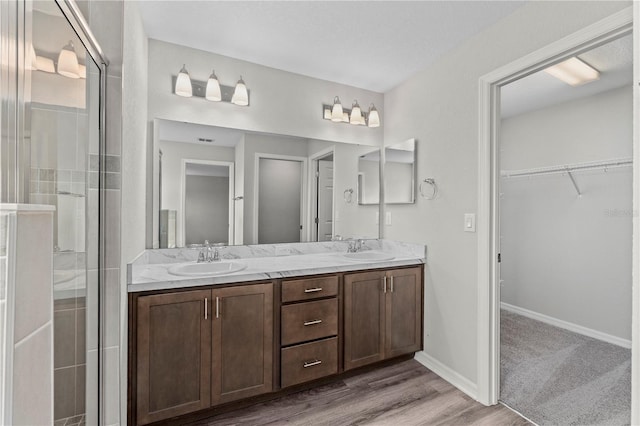 11958 Stone Pine St, Riverview, FL 33569 - bathroom featuring double vanity, a spacious closet, a tile shower, and wood finished floors