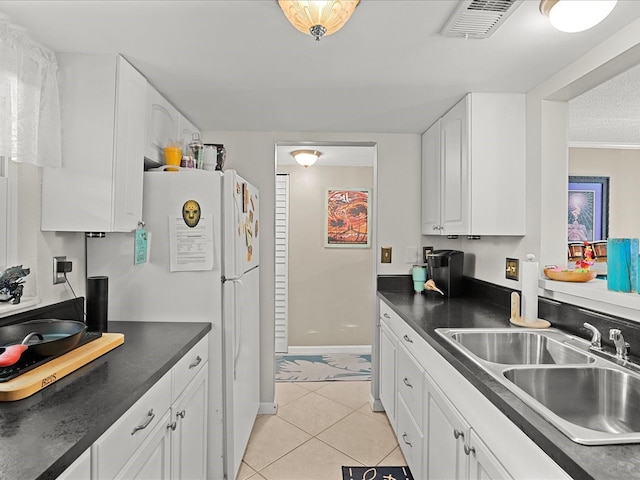 464 N Paula Dr Unit 106, Dunedin, FL 34698 - kitchen with dark countertops, white cabinets, light tile patterned floors, and freestanding refrigerator