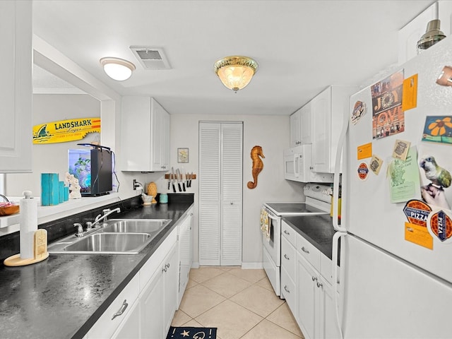 464 N Paula Dr Unit 106, Dunedin, FL 34698 - kitchen with white appliances, dark countertops, light tile patterned flooring, and white cabinets