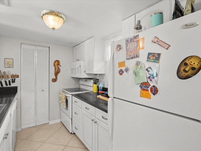 464 N Paula Dr Unit 106, Dunedin, FL 34698 - kitchen with white appliances, light tile patterned floors, dark countertops, and white cabinets