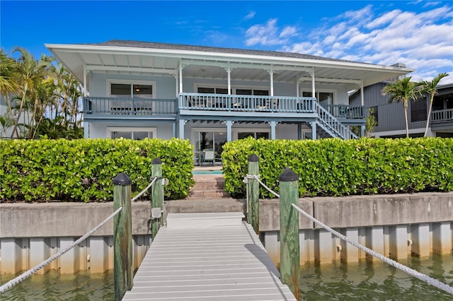 131 N Tessier Dr, St Pete Beach, FL 33706 - rear view of house with a water view, a balcony, stairs, and a shingled roof