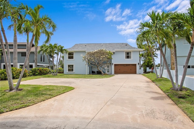 131 N Tessier Dr, St Pete Beach, FL 33706 - view of front of home with stucco siding, driveway, a garage, a front yard, and stairs