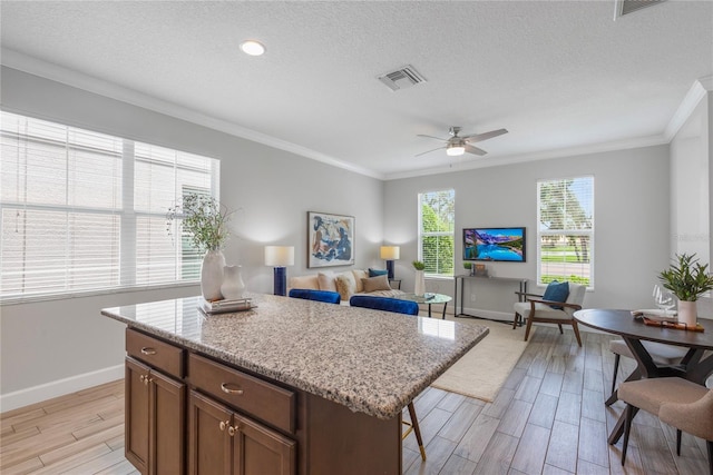 527 Jetstar Ln, Oldsmar, FL 34677 - kitchen featuring light wood finished floors, a ceiling fan, ornamental molding, a kitchen island, and a kitchen bar